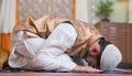 Vertical shot of young indian muslim man doing holy namaz or Salah at home during ramdan festival - concept tredition