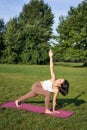 Vertical shot of young korean woman doing yoga training on rubber mat, making asana exercises on fresh air in park Royalty Free Stock Photo