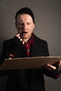 Vertical shot of a young man who holds a felttip pen in his mouth to write text on cardboard. begging concept