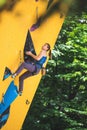 Vertical shot of a Ukrainian lady athlete climbing yellow wall on the EU Cup competition in Italy