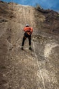 vertical shot of young sporty woman rappelling over rock wall wearing helmet and harness ropes in Costa Rica Royalty Free Stock Photo