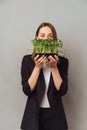 Vertical shot of a young woman holding micro greens saying be healthy.