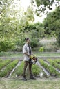 Vertical side view of young handsome man with a basket full of vegetables and the garden in the background Royalty Free Stock Photo