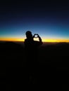 Vertical of a silhouette of a guy holding her hands in the shape of a heart against the sunset sky Royalty Free Stock Photo