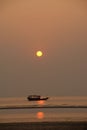 Vertical silhouette shot of a boat sailing by the coast during a beautiful sunset Royalty Free Stock Photo