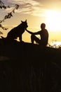 Vertical silhouette of young man and dog enjoying beautiful landscape , boy with a four-legged friend at sunset in a field, Royalty Free Stock Photo