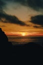 Vertical of the silhouettes of beach rocks and a dark seascape captured at sunset