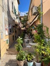 Vertical of a small alley with plants and cafe tables on a sunny day in Rovinj, Croatia
