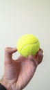 Vertical Small ball held by a hand isolated against a white wall and ceiling background