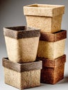 A vertical stack of eco-friendly peat pots features distinct organic textures in natural beige and dark wood-grain finishes, Royalty Free Stock Photo
