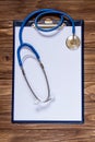 Straight clean vertical image with examination pad and stethoscope on the wooden background Royalty Free Stock Photo