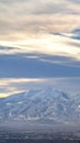 Vertical Striking sunlit mountain coated with snow under a vivid blue sky with clouds