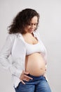 Beautiful curly haired multi ethnic pregnant woman with naked belly, isolated on background. Pregnancy 6 month. 24 weeks