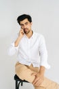 Vertical studio portrait of confident young business man in casual shirt talking smartphone with serious expression Royalty Free Stock Photo