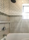 Vertical Sun flare Alcove bathtub shower combo with ceramic and subway tiles wall with mosaic tiles trim in the middle