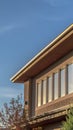 Vertical Sunlit house exterior with view of the upper storey against mountain and sky