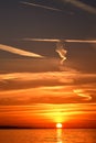 Vertical sunset over the sea with plane trails and clouds Royalty Free Stock Photo