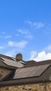 Vertical tall frame Cloudy blue sky over a home with solar panels on the pitched roof