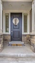 Vertical tall Home entrance with a gray front door in the middle of sidelights with blinds