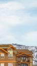 Vertical vertical, tall, magazine, Upper exterior of houses against snow covered mountain and cloudy sky in winter