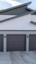 Vertical Three door garage of a lovely home against snowy slope and cloudy blue sky