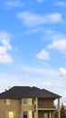 Vertical Three storey home with porch and balcony against blue sky with bright clouds