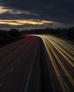 Vertical timelapse shot of car lights at night time under a sunset sky