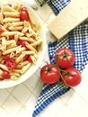 Vertical top shot of a plate full of Italian pasta with sliced cherry tomatoes and spices