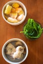 Vertical top view of the bowls with cut banans, green leaves and lemon slices with sugar