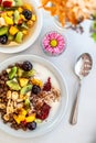 Vertical top view of bowls of muesli, yogurt, spices, and fruits