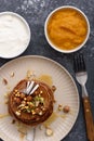 Vertical top view chocolate pancakes with hazelnuts, kiwi, coconut flakes and maple syrup in beige plate with sour cream and mango Royalty Free Stock Photo