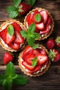 vertical top view closeup of delicious tartlets with fresh strawberry, bakery dessert with sweet berries and mint leaves on wooden Royalty Free Stock Photo