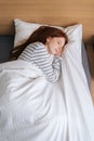 Vertical top view of cute redhead young woman sleeping well in bed hugging soft white blanket at home. Royalty Free Stock Photo