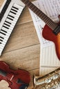 Vertical top view of different musical instruments: synthesizer, guitar, saxophone, violin lying on sheets with music Royalty Free Stock Photo