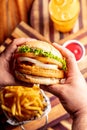 Vertical top view of hands holding a thick gourmet juicy burger