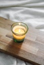 Vertical top view of a litten candle on a wooden board, on a white comforter Royalty Free Stock Photo