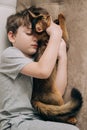 Vertical top view little kid boy lying on the couch and hugging his fluffy tail red cat kitten of somaly breed. Royalty Free Stock Photo