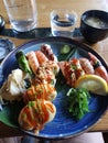 Vertical top view of a meal with shrimps and sushi served on a blue plate Royalty Free Stock Photo