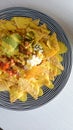 Vertical top view of a plate of nachos with sauce on a white surface Royalty Free Stock Photo