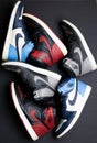 Vertical top view of red, gray, and blue pairs of Nike banned Air Jordan 1 over the black surface