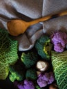 Vertical top view shot of numerous types of green vegetables with a wooden spoon beside them