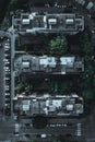 Vertical top view of three identical apartment buildings with trees and cars on the street