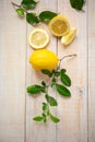 Vertical top view of whole and sliced lemons decorated with lemon tree leaves to resemble flowers