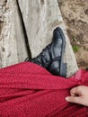 Vertical top view of a woman wearing black boots and a red skirt, sitting on a bench at the beach Royalty Free Stock Photo