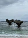 Vertical of the tourist attraction Heart Rock in Japan getting watered by foamy ocean waves