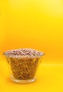 Vertical of a transparent bowl full of dry lentils isolated on a yellow background Royalty Free Stock Photo