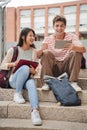 Vertical Two teenagers sitting on the university campus stairs, studying lessons and doing homework using a tablet Royalty Free Stock Photo