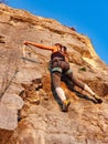 VERTICAL: Unrecognizable female rock climber scales a wall on a sunny evening.