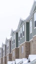 Vertical Upper storey of townhomes with brick wall vertical siding and snowy roofs