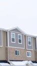 Vertical Upper storey of townhomes with snowy pitched roofs on a cold winter day